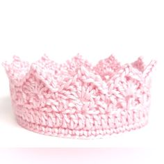 a crocheted pink crown sits on a white surface