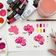 a person is painting flowers with watercolors and other paints on a white table