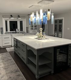 a large kitchen island with lots of counter space and lights hanging from it's ceiling