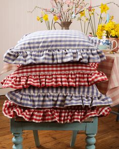 three pillows stacked on top of each other in front of a table with vases and flowers