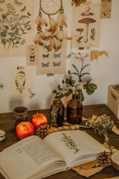 an open book sitting on top of a wooden table next to apples and other items