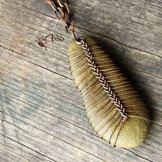 a close up of a necklace on a wooden surface with a chain hanging from it