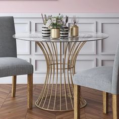 a dining table with two chairs and a vase on it in front of a wall