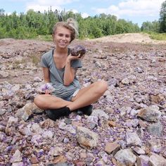 a woman is sitting on the ground with rocks and holding a rock in her hand