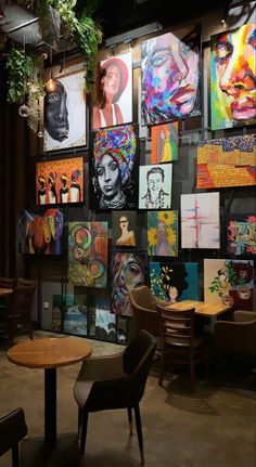a room filled with lots of paintings on the wall next to a table and chairs