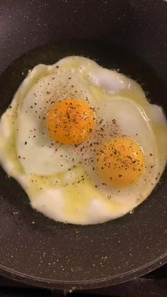 two fried eggs in a frying pan on the stove