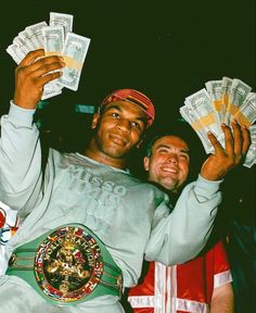 two men are holding up money in front of their faces and one is wearing a green belt