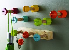 colorful wooden pegs are hanging on the wall next to a key rack and vase