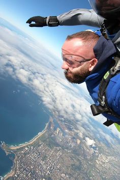 a man flying through the air while wearing a helmet and holding onto a parachute over a city