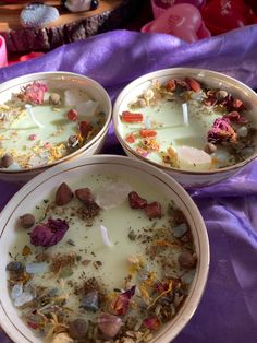 three bowls filled with food on top of a purple cloth