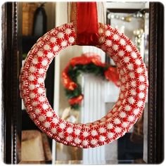 a red and white christmas wreath hanging from a door