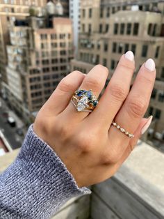 a woman's hand holding an engagement ring on top of a building