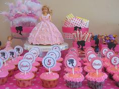 there are cupcakes with pink frosting and decorations on the table for barbie's birthday party