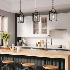 a kitchen with white cabinets and wooden stools in front of the counter top is lit by three hanging lights