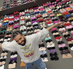 a man standing in front of rows of bras with his arms spread wide open