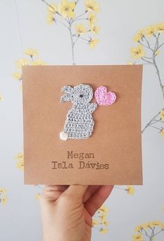 a person holding up a card with a crocheted bunny and heart on it