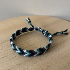 a close up of a rope bracelet on a table with a white wall in the background