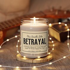 a lit candle sitting on top of a wooden table next to a string of lights