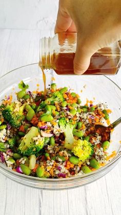 someone pouring dressing into a glass bowl filled with vegetables