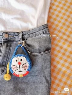 a close up of a person's jeans with a cat keychain on it