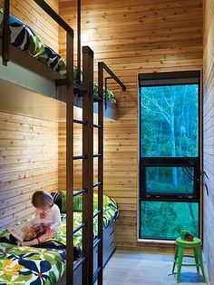 a child is sitting on a bunk bed in a room with wooden walls and flooring