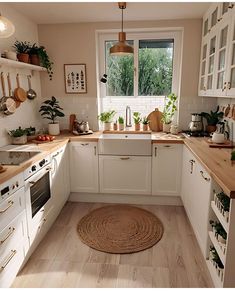 a kitchen filled with lots of white cabinets and wooden counter tops next to a window