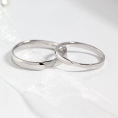 two wedding rings sitting on top of a white cloth