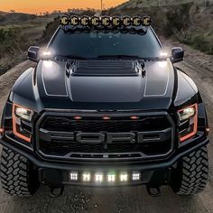 the front end of a black truck on a dirt road