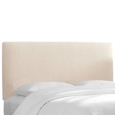 a bed with white sheets and pillows on top of it's headboard, in front of a white wall