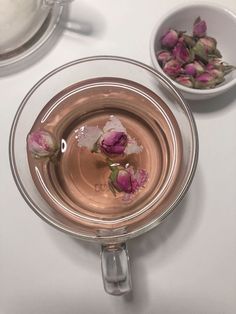 two bowls filled with flowers on top of a white table next to a tea pot