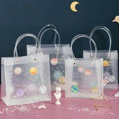 three clear bags with space images on them and a small white vase next to it