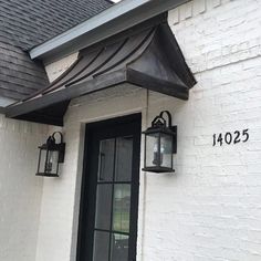 a white brick house with two lanterns on the front door