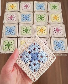 someone is holding up a crocheted square with small flowers on it and the squares are