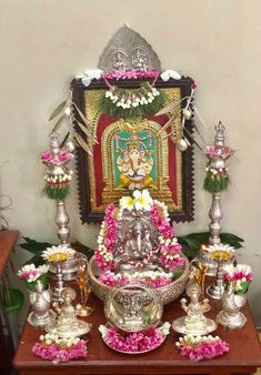 an idol is displayed on a table with flowers and other items around it, as well as candles