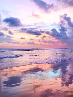 the sky is reflected in the wet sand at the ocean's edge as the sun sets