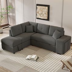 a living room with a gray sectional couch and book on the floor in front of it