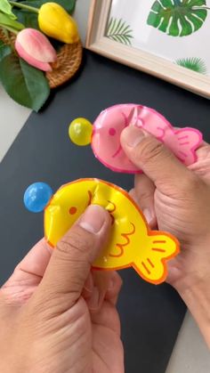 a person is holding two small fish magnets