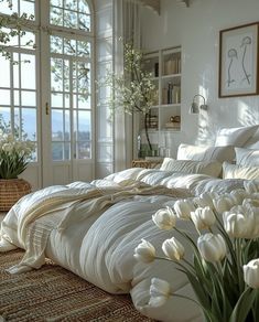 white tulips are in a vase on the floor next to a large bed