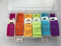 several different colored sewing needles in a plastic case