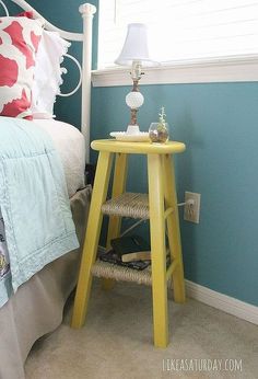 a bedroom with blue walls and a yellow stool in front of the bed that's up against the wall