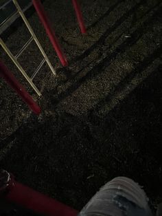 a red fire hydrant sitting on top of a field next to a metal pole