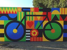 a large colorful painting on the side of a building with a bicycle painted on it