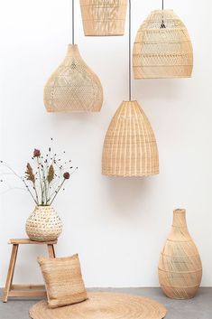 wicker lamps hang from the ceiling above a stool and table with flowers in vases