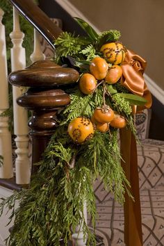 an arrangement of oranges and greenery on the banister