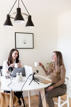 two women sitting at a table with laptops and coffee cups in front of them