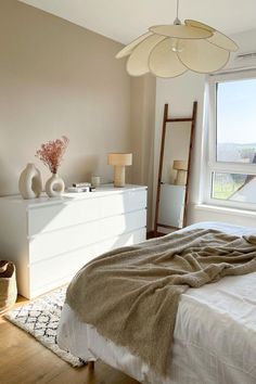 a bedroom with a bed, dresser and large window in it's center area