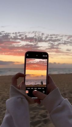 someone taking a photo with their cell phone on the beach at sunset or sunrise time