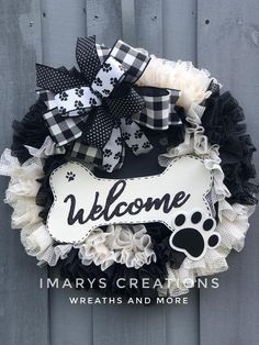 a black and white wreath with a dog's paw on it that says welcome mary's creations