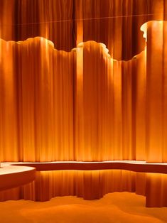 an orange curtained room with a bench in front of it