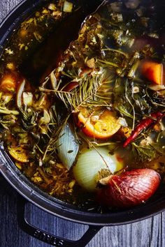 a pot filled with soup and vegetables on top of a wooden table